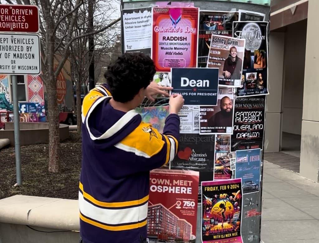 David Skadron posting a Dean Phillips for President flyer in Madison